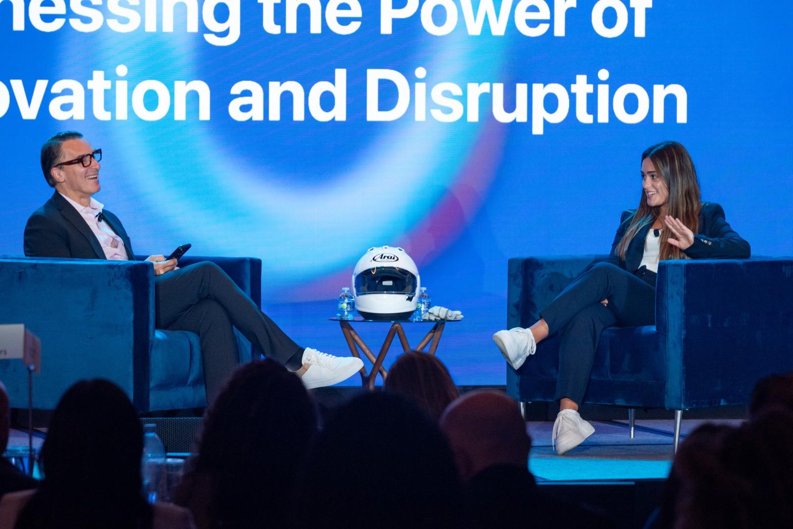 Maite Cáceres on stage at a Hewlett Packard Enterprise event, her helmet on the table