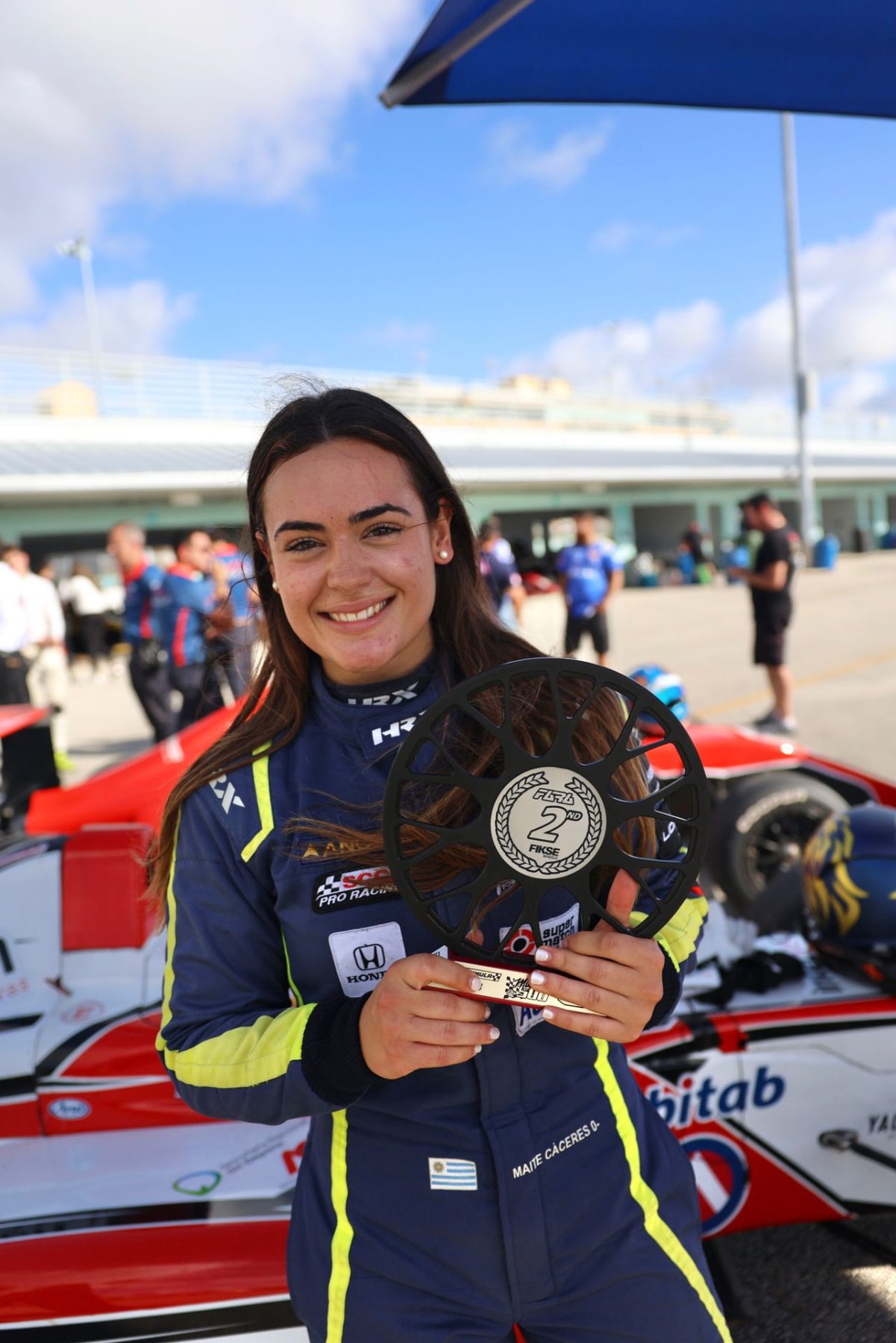 Maite Cáceres holding her trophy in the paddock