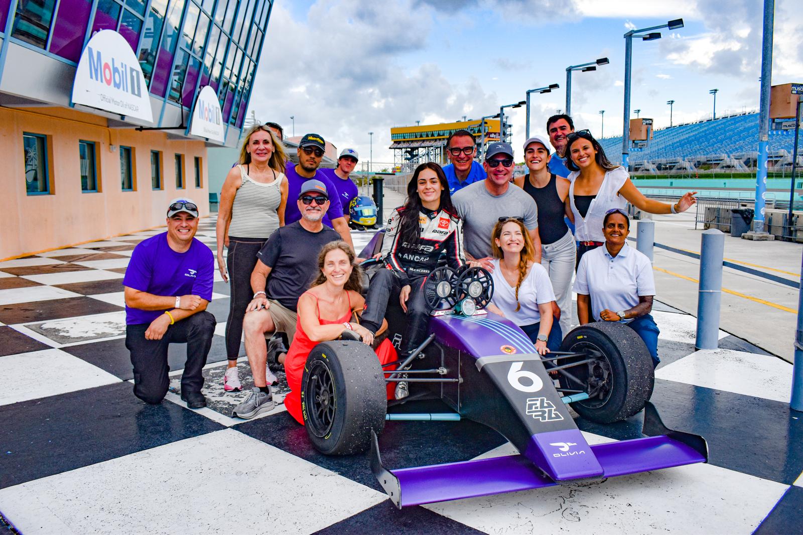 Guests gathered around Maite's race car at a track experience