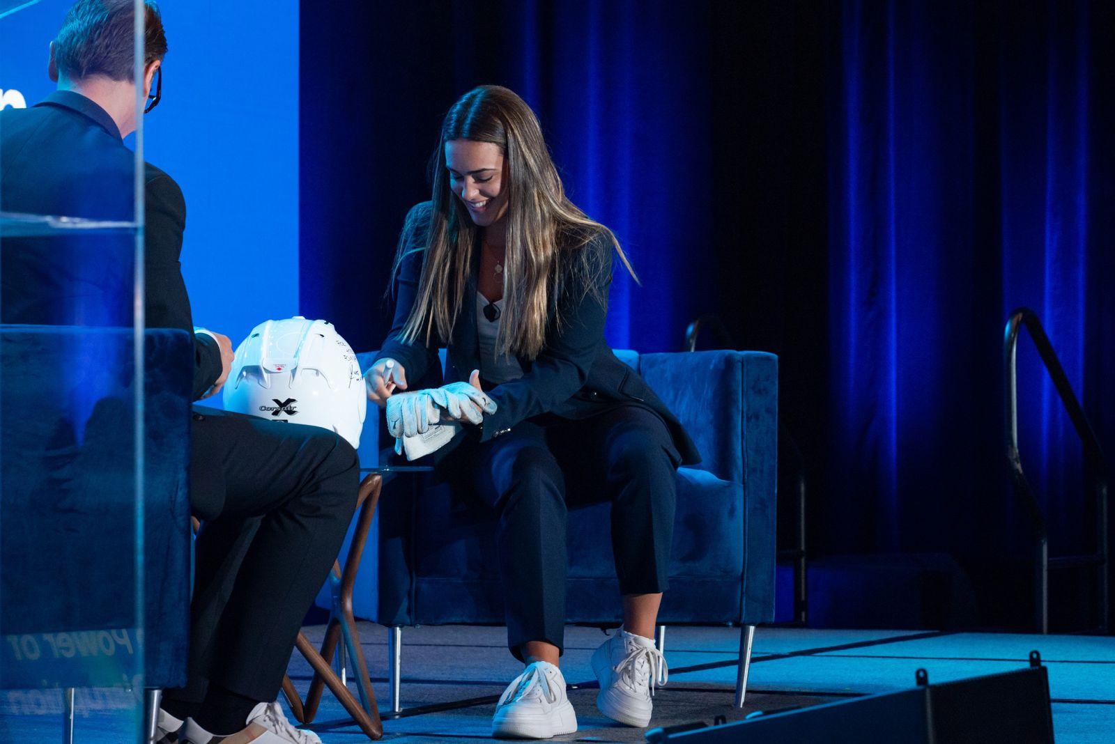 Maite signing a helmet on stage at HPE